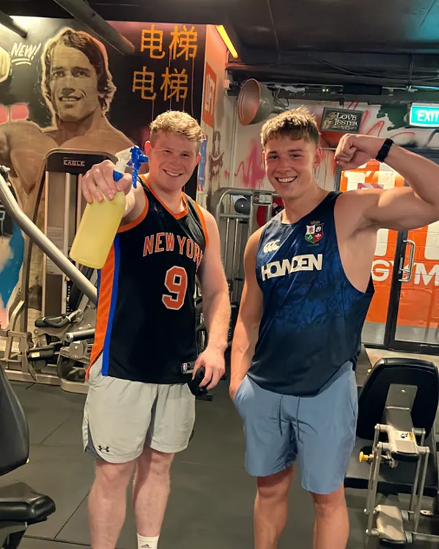 Two LiFT members flexing in front of the mural