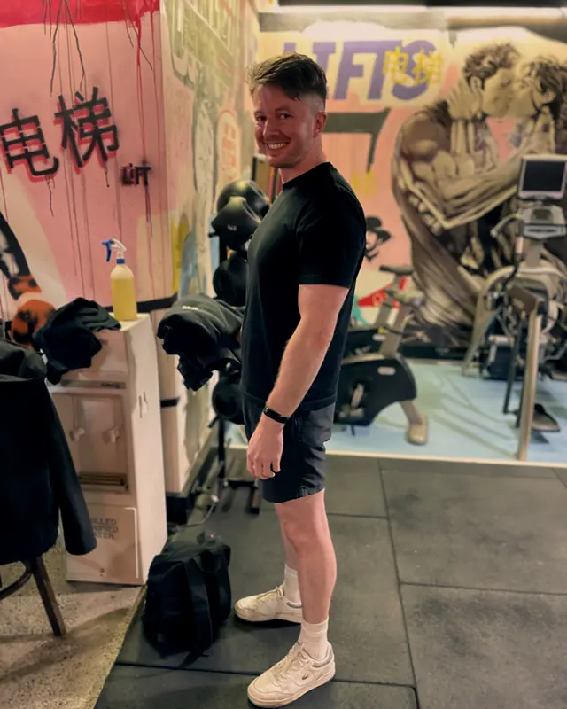 A member smiling beside the mural wall