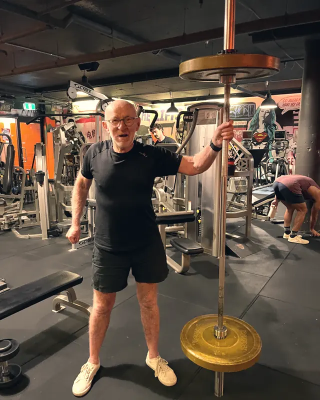 A LiFT member holding a barbell overhead