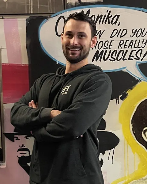 Curtis Lamprecht with arms folded in front of the LiFT mural
