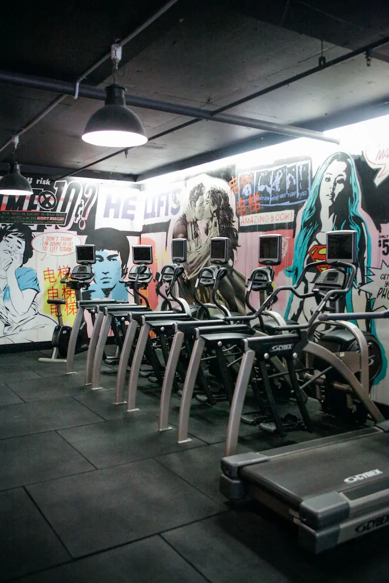 Row of cardio machines under the murals