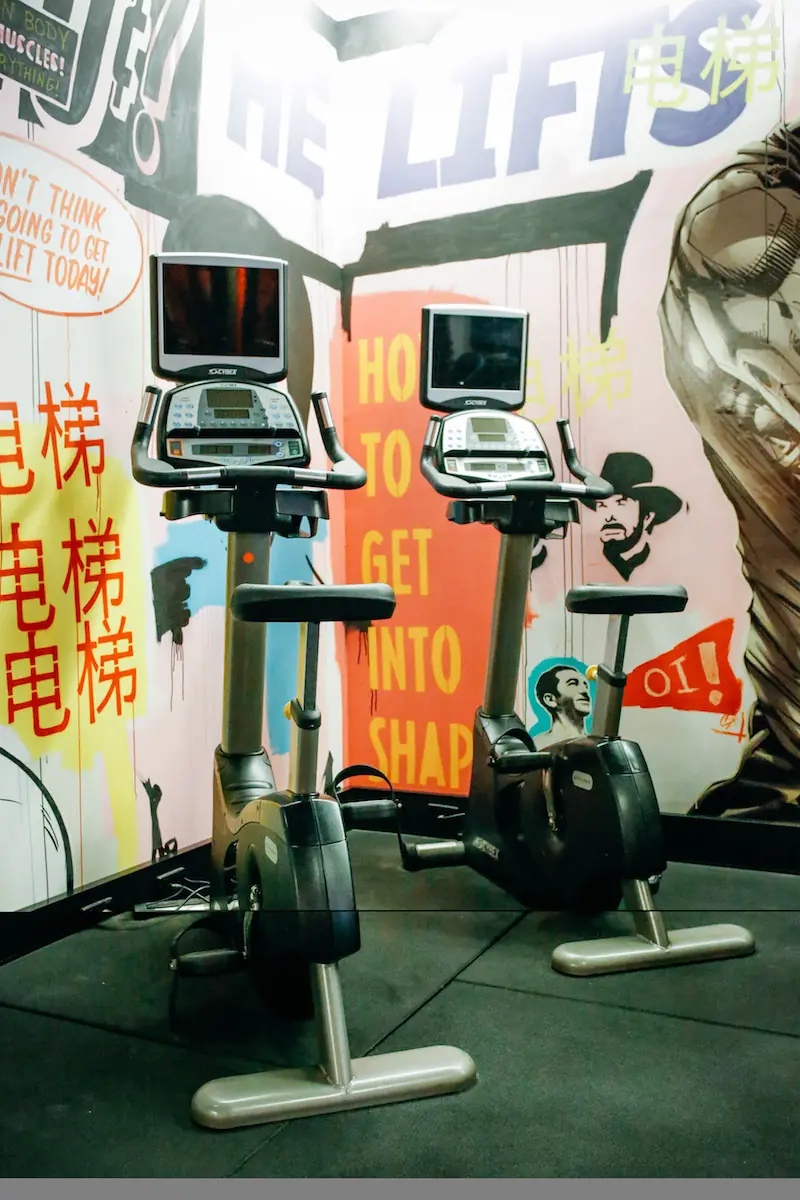 Exercise bikes under the “He lifts” mural