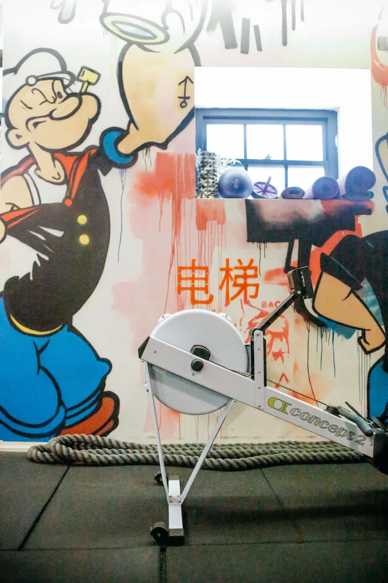 Rowing machine in front of a Popeye mural