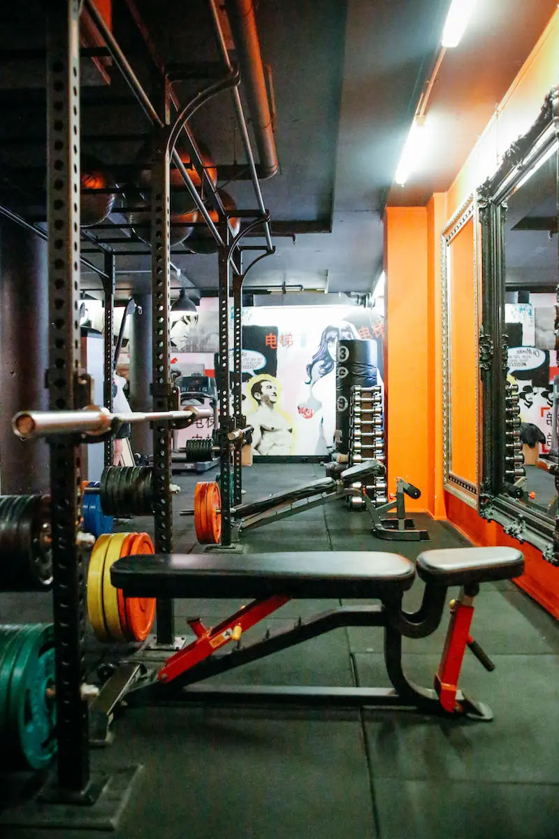 Flat bench in front of a squat rack by the orange wall