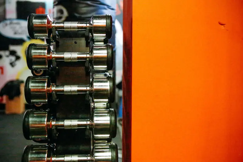 Row of heavy dumbbells beside an orange wall