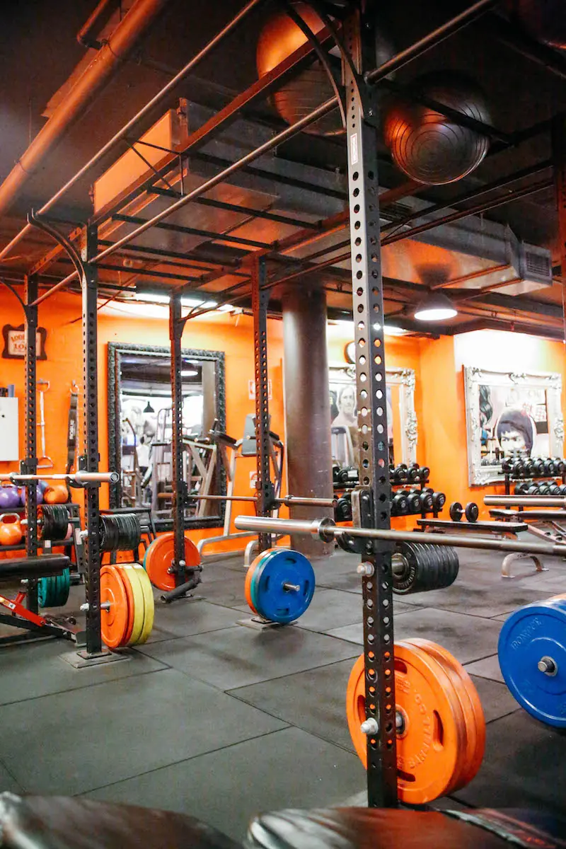 Power rack and bumper plates under the orange lights