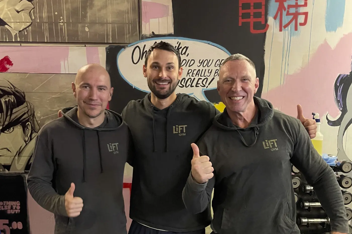 Three LiFT coaches smiling in front of the mural